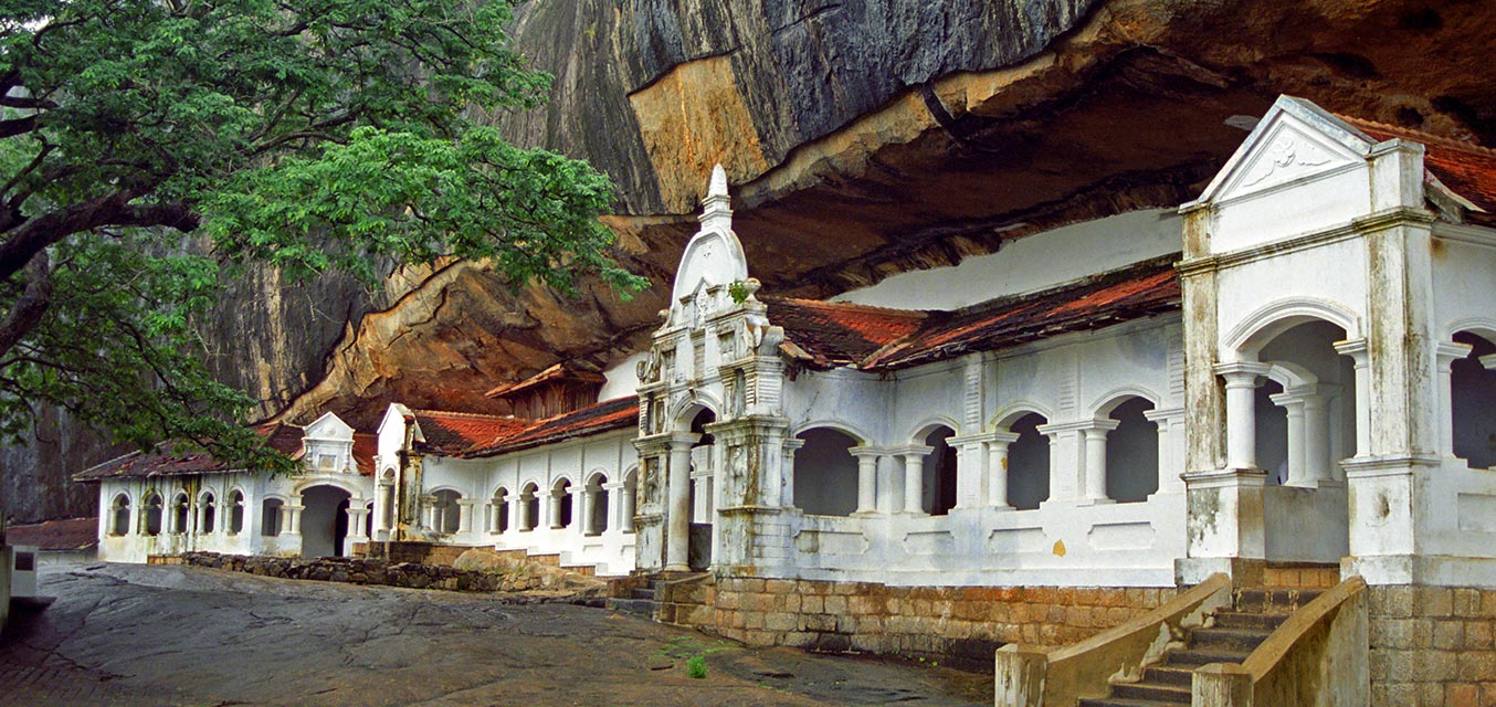 En bild på Dambulla grottempel, en vit byggnad i en stor grottöppning.